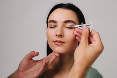 Göz kapaklarını düzeltmek için birofaroplasti hazırlıyorum. Üst blefaroplasti. Plastik cerrah, Castroviejo kalibreli hastasının gözünün içindeki cerrahi mesafeyi ölçüyor.