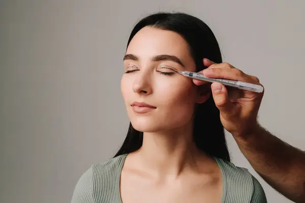 Üst Blepharoplasty. Cerrah, hastanın göz kapağına doğru ameliyat için işaretleme çizgileri çiziyor. Cerrah üst blefaroplasti işlemini planlıyor.