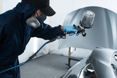 Araba boyacısı aracın rengini sünger ve boya spreyi kullanarak değiştiriyor. İşçi arabayı HVLP sprey tabancasıyla koyu renklere boyuyor.