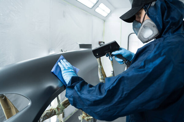 Using anti static gun to prevent damages and remove dust before covering car with paint. Mechanic is working with anti static gun to prepare metal for paintwork.
