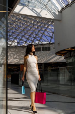 Makyaj malzemesi ve aksesuar almak. Sevgililer Günü için sevimli hediyeler hazırlıyorum. Güzel esmer bayan alışveriş merkezinde bir çanta dolusu mal taşıyor.