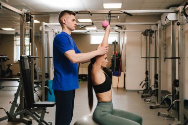 Kineziyoterapi. Genç bir kadın egzersiz topunda terapi amaçlı jimnastik yapıyor. Yaralanmayı önlemek için kinezi yapıyorum.