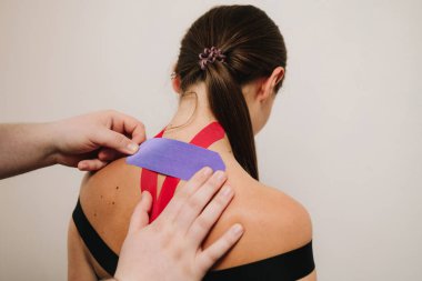 Tıbbi bant. Doktor ağrıyı ve iltihabı azaltmak için sporculara parlak kinezyoloji bandı uyguluyor. K-bantlarıyla lenf kanserinden iyileşme