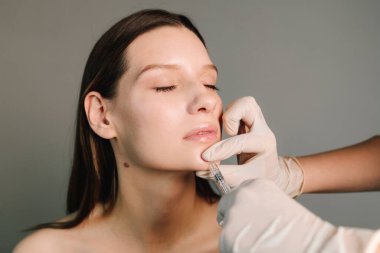 Çene çizgisi ve çene şeklini değiştiriyor. Yüksek kalite enjeksiyonlar. Çekici bir kız için estetik klinikte yüz doldurucu iğneler.