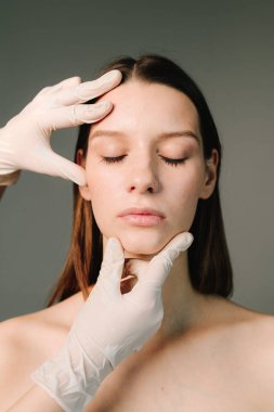 Yüz geliştirme. Yüzün şeklini düzeltmek için konturer plastik. Güzellik tedavisi için marka deri. Doktor kadın tenini güzel yüz hatlarına hazırlar..