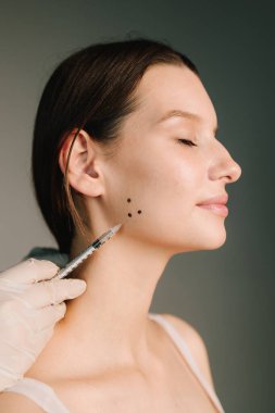 Estetik tıp kliniğinde botulinyum toksinle tedavi için Bruksisizm yüz işareti. Bir kozmetikçi tarafından diş gıcırdatma için Bruksizm işareti