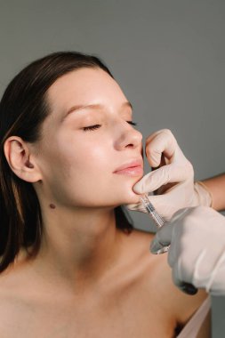 Çene çizgisi ve çene şeklini değiştiriyor. Yüksek kalite enjeksiyonlar. Çekici bir kız için estetik klinikte yüz doldurucu iğneler.