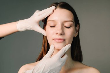 Yüz geliştirme. Yüzün şeklini düzeltmek için konturer plastik. Güzellik tedavisi için marka deri. Doktor kadın tenini güzel yüz hatlarına hazırlar..