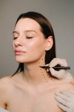 Nefertiti kaldırmadan önce işaretle. Kozmetik uzmanı bir kadının platizmasına botulinyum toksin enjekte edilmeden önce nokta çiziyor. Bir profesyonelden boyun geliştirme. Kadın estetik kozmetolojisi