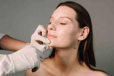 Çekici bir kız için estetik klinikte yüz doldurucu iğneler. Çene çizgisi ve çene şeklini değiştiriyor. Yüksek kalite doldurucu enjeksiyonları.