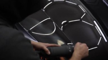 Araba cilalama ve 4K video detayı. Yörünge parlatıcısı olan eller, temizlik merkezinde siyah araba cilalayan. Yörüngesel cilalayıcı ile cilalanan sert balmumu araba yakın plan çizikleri kaldırmak için.