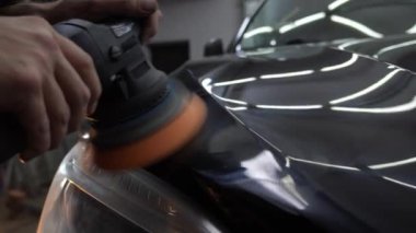 Yörünge cilasıyla cilalanan Hard Wax 'ın 4k' lık videosu yakın plan çizikleri silmek için. Araba cilalama ve detaylı işlemler. Yörünge parlatıcısı olan eller, temizlik merkezinde siyah araba cilalamak..