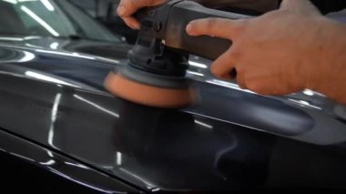Araba cilalama ve 4K video detayı. Yörünge parlatıcısı olan eller, temizlik merkezinde siyah araba cilalayan. Yörüngesel cilalayıcı ile cilalanan sert balmumu araba yakın plan çizikleri kaldırmak için.