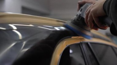 Yörünge cilasıyla araba cilalamak 4K 'lık çizikleri silmek için. Otomobil servisi çalışanı araba için son cilalamayı yapıyor.