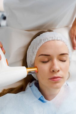 Removal rosacea of dilated small vessels on patient face with IPL ultrasound laser. Laser treatment of rosacea by dermatologist. Painless rosacea treatment in beauty clinic clipart