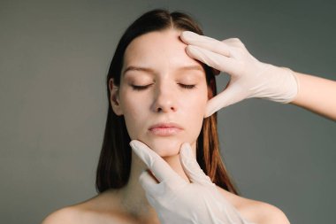Doktor kadın tenini güzel yüz hatlarına hazırlar. Yüzün şeklini düzeltmek için konturer plastik. Güzellik tedavisi için işaretlenmiş deri