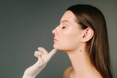 Doktor kadın tenini güzel yüz hatlarına hazırlar. Yüzün şeklini düzeltmek için konturer plastik. Güzellik tedavisi için işaretlenmiş deri