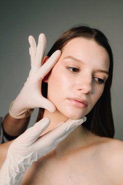 Estetik ve güzel şekiller için yüz bakımını düzeltiyorum. Kadın hatlı plastik. Güzellik uzmanıyla genç bir kadının yüz şeklini düzeltiyorum.