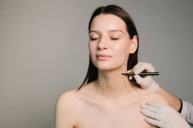 Kozmetik uzmanı bir kadının platizmasına botulinyum toksin enjekte edilmeden önce nokta çiziyor. Nefertiti kaldırmadan önce işaretle. Bir profesyonelden boyun geliştirme. Kadın estetik kozmetolojisi