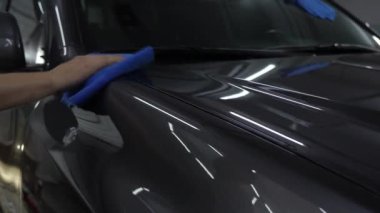 Detaylı serviste mikro fiber bez kullanarak araba cilalamak. Bir aracı cilalamak ve cilalamak. Temizlik servisinde havluyla araba valesi..