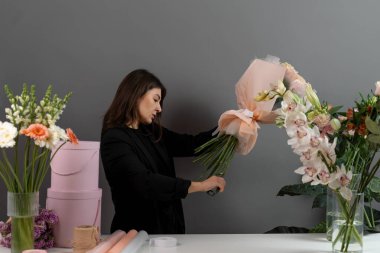 Çiçek aranjmanının sırasına göre budama sapları. Çiçekçide makasla çiçek sapını kesmek. Çiçekçinin bitki bakımı