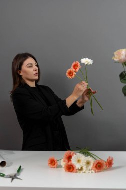 Müşteriler için Gerberas 'tan çiçek kompozisyonu hazırlıyorum. Çiçekçi çiçekçide çiçek toplamak için papatya çiçeği topluyor.