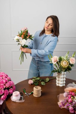 Stüdyoda çiçek buketi yapan bir çiçekçi. Beste yapmadan önce taze çiçekler hazırlıyorum. Kadın çiçekçi bir buket kompozisyon tutuyor ve dizayn ediyor.