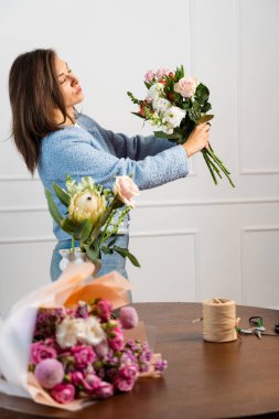 Stüdyoda çiçek buketi yapan bir çiçekçi. Beste yapmadan önce taze çiçekler hazırlıyorum. Kadın çiçekçi bir buket kompozisyon tutuyor ve dizayn ediyor.