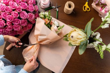 Buket kompozisyonunu güzel taze çiçeklerle el sanatları kağıdına sarmak. Çiçekçinin çiçekçide bir buket karışık çiçek açması.