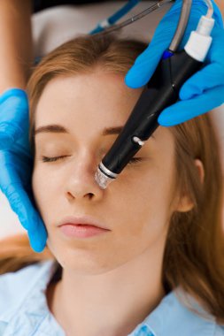 Bir kadın için yüz hidrosiyali cilt temizleme ameliyatı yapan bir güzellik uzmanı. Klinikte acısız yüz temizleme. Güzellik merkezinde tıbbi aletle Hidroseksüel Temizleme Prosedürü