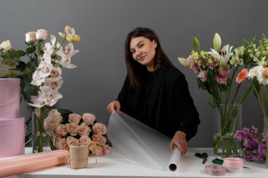 Çiçekçi çiçek aranjmanı için ambalaj kağıdını makasla kesiyor. Çiçek buketi yapmak için çiçek süsleme hazırlıyorum.