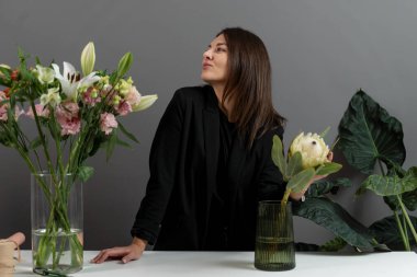 Teslimat için protea buketi yapıyorum. Kompozisyon yapmak için hazırlık çiçekleri. Çiçekçi elinde bir protea çiçeği tutuyor ve çiçeklerin sapını kesiyor.