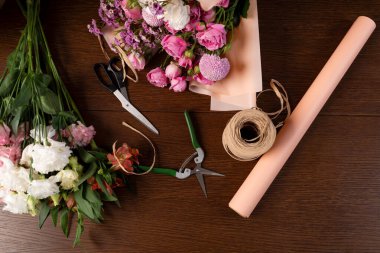 Çiçekçinin çiçek buketlerini el işi kağıdına sarmak. Çiçek stüdyosunda karışık çiçek kompozisyonları topluyorum. Bir buket oluşturma süreci