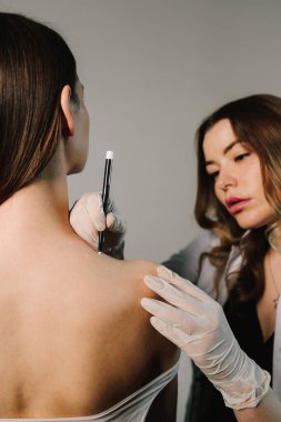 Migrenden kalma deri ve terapi için ağrı kesici. Yüksek kaliteli bir uzman tarafından acısız tedavi. Doktor, migren tedavisi için sırt derisine işaretler çizer.