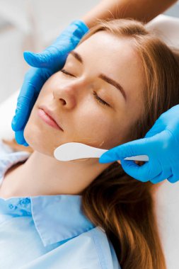 Kozmetik uzmanından cilt bakımı için hidrojel maske almak. Güzellik kliniğinde lazer yüz tedavisinden önce kadının yüzüne hidrojel maske takmak.