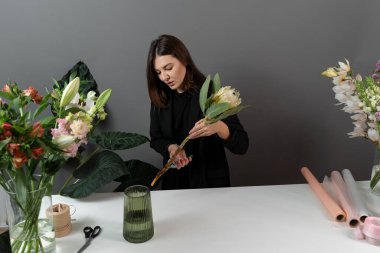 Çiçekçi bir protea çiçeği tutuyor ve çiçek atölyesinde çiçeğin sapını kesiyor. Teslimat için protea buketi yapıyorum. Kompozisyon yapmak için hazırlık çiçekleri