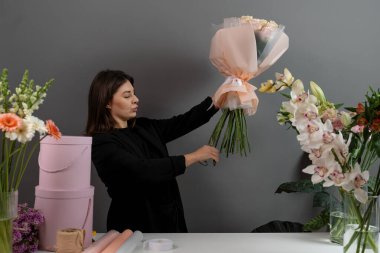Çiçek aranjmanının sırasına göre budama sapları. Çiçekçide makasla çiçek sapını kesmek. Çiçekçinin bitki bakımı