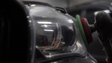 Yörünge parlatıcısı olan eller, 4k 'lık bulanık farları onarmak için detaylı merkezde siyah araba cilalamak. Yörüngesel cilalayıcı ile sert balmumu araba far cilalama çizikler kaldırmak için.