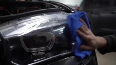 Yörünge parlatıcısı olan eller, 4k 'lık bulanık farları onarmak için detaylı merkezde siyah araba cilalamak. Yörüngesel cilalayıcı ile sert balmumu araba far cilalama çizikler kaldırmak için.