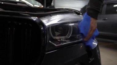 4K video servisinde mikro fiber bez kullanarak araba farlarını parlatmak. Bir aracı cilalamak ve cilalamak. Farları havluyla silmek. Profesyonel araba temizliği.