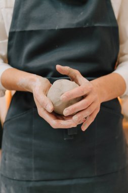 Çömlekçi kız atölyede seramik bir alet yapıyor. Çömlekçi kadın çömlek atölyesinde ıslak kille çalışıyor.