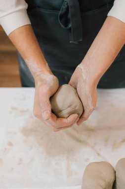 Çömlekçi kız atölyede seramik bir alet yapıyor. Çömlekçi kadın çömlek atölyesinde ıslak kille çalışıyor.
