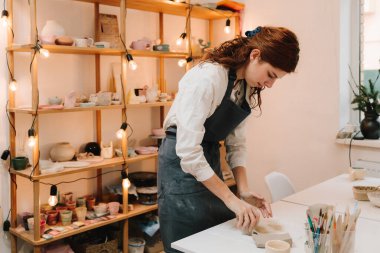 Toprak malzemesi yapmak için kil yontuyorum. Sanat stüdyosunda kadın esnaf kil kalıplar çıkarıyor.