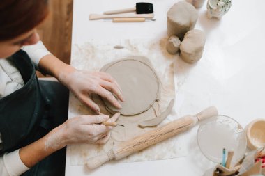 Genç çömlekçi atölyede çömlekçilikle bir çember keser. Kil modelleme için hazırlanılıyor, kapatılıyor