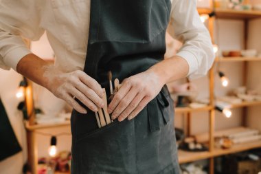 Farklı çömlekçi enstrümanları. Esnaf siyah önlüğü farklı çömlekçi aletleri taşır.