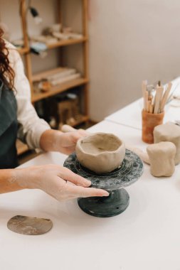 Kadın çömlekçi elleri seramik kasenin fırında ateşe hazır olduğunu gösteriyor. Seramik ürünler oluşturma süreci