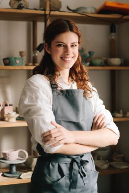 Onun çömlekçi stüdyosunun arka planında toprak eşyalarıyla dolu raflarla mutlu bir genç çömlekçi duruyor ve gülümsüyor. Küçük işletmeleri başarılı bir zanaatkar kadın yönetiyor.