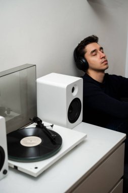Romantik müzik aşığı, LP çalan eski bir klasik albümün retro vinil müziğinin keyfini çıkarıyor. Evde modern vinil hoparlör sistemine sahip Hi-Fi ses