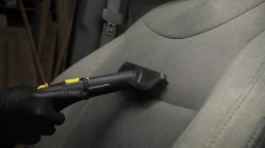 Otomobil 4K videosunu dezenfekte etmek ve temizlemek için buhar makinesini kullanarak arabadaki koltukları buharla temizliyor. Buharlı araç koltuklarının ayrıntıları temiz.