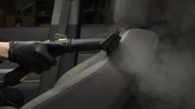 Otomobil 4K videosunu dezenfekte etmek ve temizlemek için buhar makinesini kullanarak arabadaki koltukları buharla temizliyor. Buharlı araç koltuklarının ayrıntıları temiz.